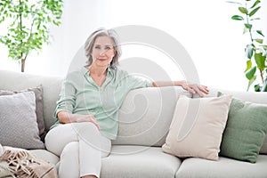 Photo of calm peaceful pretty old woman sit sofa good mood wekend wear casual outfit inside house home indoors