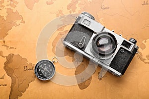 Photo camera and compass on vintage world map. Travel planning concept