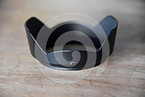 Photo camera lens hood,in black color,placed on brown wooden background