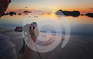 Photo camera on tripod beach sea sunset. Hobby travel photography concept. Beautiful sea landscape