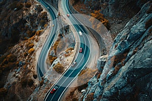 This photo captures an aerial perspective of a curving road nestled amidst the majestic mountains, Cars winding their way up a