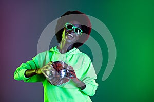 Photo of carefree disco 80s style lady hold glowing ball wear sunglass hoodie isolated gradient green neon background