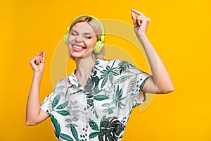 Photo of carefree funky woman dressed print shirt earphones dancing empty space isolated yellow color background