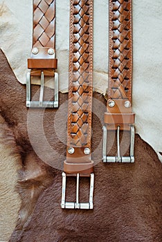 Photo of carton leather three leather brown belts on fur and leather backgroundhandmade notebook on leather background