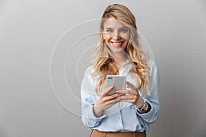 Photo of caucasian blond businesswoman with long curly hair smiling and holding smartphone