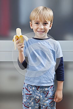 Portrait of Caucasian boy in casuals holding banana photo