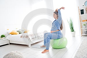 Photo of charming adorable pregnant girl sitting on fitnessball exercising yoga meditation aerobics stretching daylight