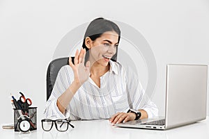 Photo of charming brunette businesswoman using laptop in office isolated over white background