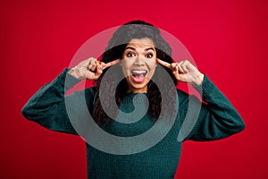 Photo of charming cheerful dark skin young woman cover fingers ears smile isolated on red color background