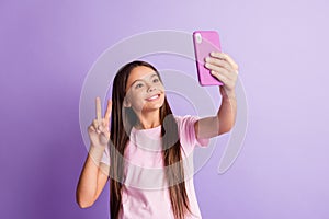 Photo of charming cute schoolgirl dressed t-shirt tacking selfie modern device showing v-sign isolated purple color