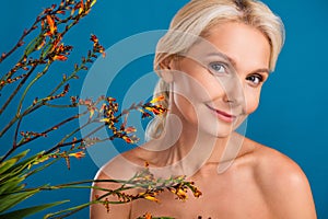 Photo of charming cute senior woman nude shoulders smiling enjoying natural cosmetics products isolated blue color