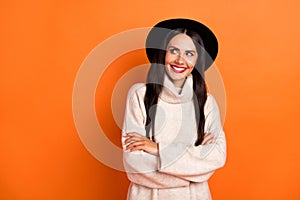 Photo of charming cute young lady dressed beige pullover cap arms crossed looking empty space isolated orange color