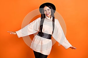 Photo of charming cute young woman wear beige sweater headwear hands arms sides isolated orange color background