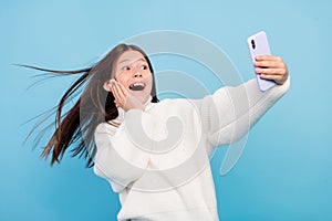 Photo of charming excited student girl wear white sweater smiling tacking selfie arm cheek isolated blue color