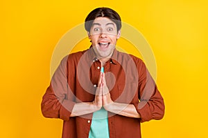 Photo of charming excited young man wear brown shirt asking but new things isolated yellow color background
