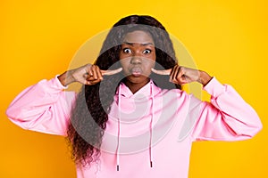 Photo of charming fooling dark skin woman dressed pink hoodie fingers pressing bloated cheeks isolated yellow color