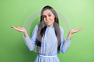 Photo of charming funny young woman dressed blue outfit shrugging shoulders isolated green color background