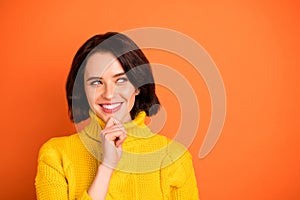 Photo of charming girl thinking on how to realize something while isolated with orange background