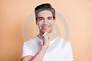 Photo of charming happy man hold hand chin think positive idea isolated on pastel beige color background