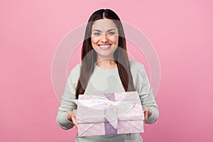 Photo of charming happy nice young woman give present you smile isolated on pastel pink color background