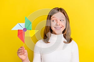 Photo of charming happy pretty little girl hold look windmill toy smile isolated on yellow color background