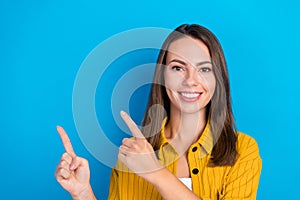 Photo of charming happy young woman point finger empty space comment follow news isolated on blue color background