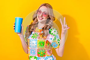 Photo charming lady drink nonalcohol cocktail paper cup show v sign wear heart sunglass print shirt  yellow