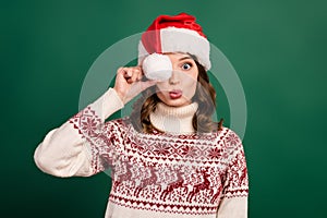 Photo of charming lady pouted lips kiss arm hold headwear pompom ball cover eye isolated on green color background