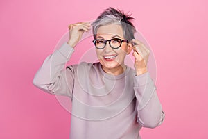 Photo of charming lovely positive retired woman wear trendy clothes hold hair short haircut isolated on pink color