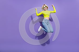 Photo of charming overjoyed girl wear trendy bright clothes celebrate success jump empty space isolated on purple color