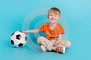 Photo of charming positive cute boy sitting floor enjoy hobby like football watching final league isolated on cyan color