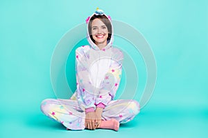 Photo of charming pretty young lady unicorn sleepwear sitting floor smiling isolated turquoise color background