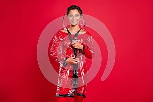 Photo of charming shiny young woman dressed rubber coat hood smiling isolated red color background