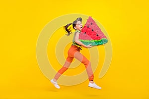 Photo of charming sweet preteen girl dressed green top jumping high biting huge watermelon slice smiling isolated yellow