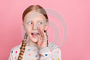 Photo of charming tricky school girl wear pullover arm mouth telling you secret looking empty space isolated pink color