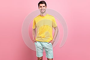 Photo of charming young happy man hold hands pockets good mood smile isolated on pink color background