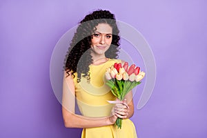 Photo of charming young lady hold bunch tulips look camera wear yellow dress isolated violet background