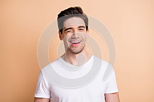 Photo of charming young man wink eye cheerful mood wear white t-shirt isolated on beige color background