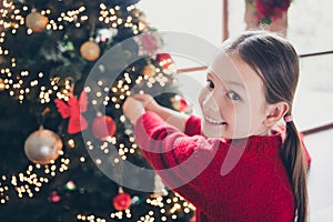 Photo of cheerful adorable girl toothy smile enjoy hanging toys christmastime festive tree apartment indoors