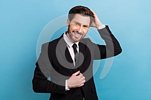 Photo of cheerful attractive man manager wear black tuxedo fixing hairdo isolated blue color background