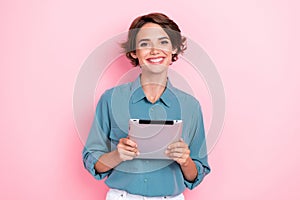 Photo of cheerful charming girl toothy smile hold tablet isolated on pink color background