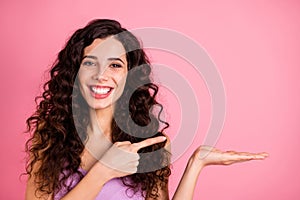 Photo of cheerful cute charming pretty girlfriend pointing at object in on her palm while isolated with pink background