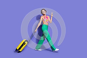 Photo of cheerful cute good mood girl wear trendy clothes go airport fly abroad sea resort vacation isolated on purple