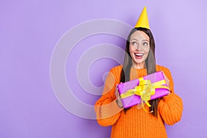 Photo of cheerful dreamy lady hold gift anticipate wish fulfillment wear orange sweater isolated violet color background