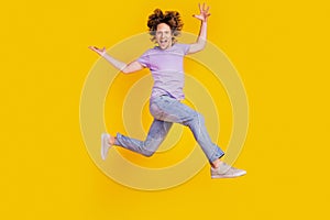 Photo of cheerful energetic man jump raise hands have fun run wear casual jeans clothes on yellow background