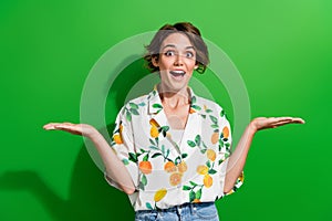 Photo of cheerful excited girl two arm demonstrate empty space recommend buy nice quality product isolated on green