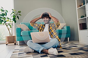 Photo of cheerful excited man sit on floor comfort room hands touch head hired in business company it specialist vacancy