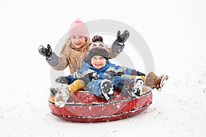 Photo of cheerful girl and boy riding tubing