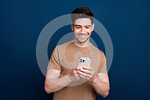 Photo of cheerful glad man wear beige trendy clothes writing typing sms post comment repost isolated on dark blue color