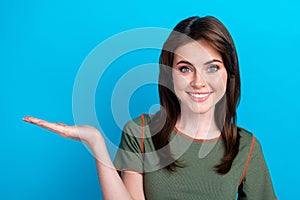Photo of cheerful gorgeous girl toothy smile hand palm hold empty space isolated on blue color background